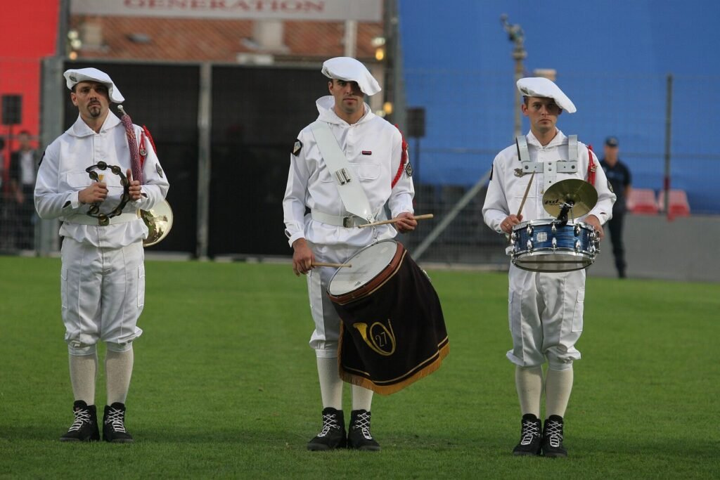 Trois musiciens de la fanfare du 27e bataillon de chasseurs alpins en tenue blanche, coiffés de la tarte blanche