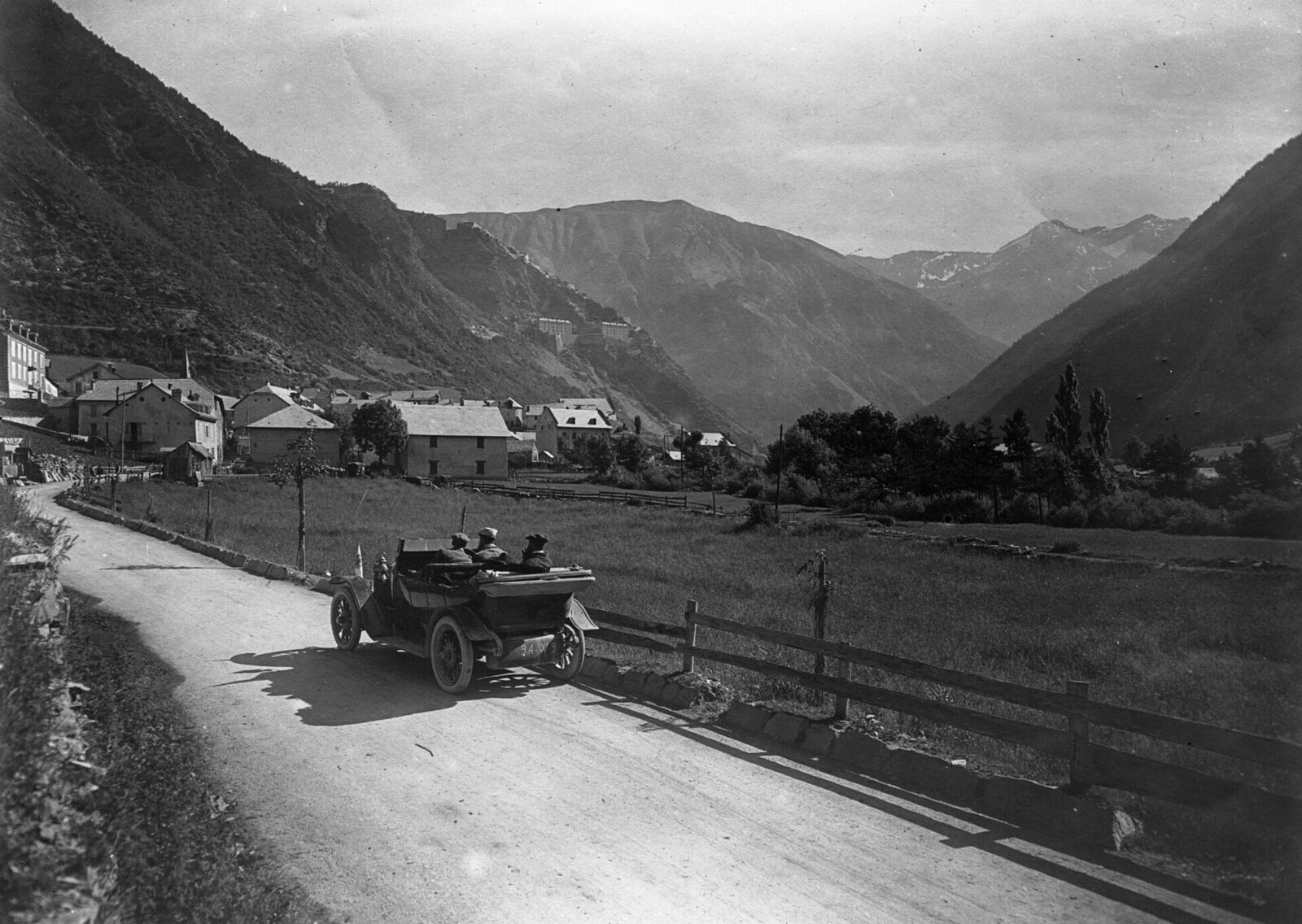 Route de La Condamine avec une automobile ancienne au premier plan et le fort de Tournoux sur la pente de la montagne à l'arrière-plan
